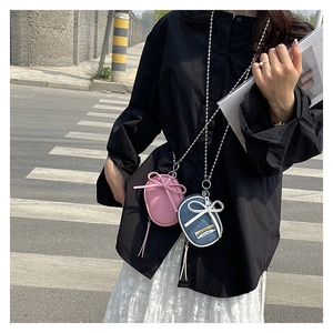 Detalle de mini bolsos bandolera ovales con lazos y cadenas de cuentas plateadas de moda
