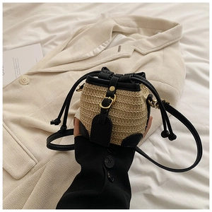Détail du mini sac seau en paille avec garniture en cuir noir et boucle dorée chic