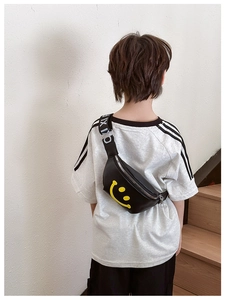 Back view of a child wearing a black waist bag with yellow smiley face and letter strap