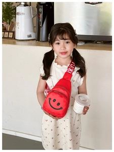 Close-up of red kids chest bag with smiley face print and letter strap on a girl