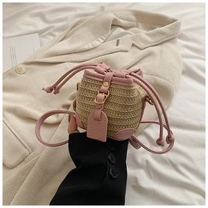 Détail du cordon en cuir rose et des bordures sur un mini sac seau en paille