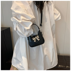 Détail d'un mini sac à main noir pour enfant avec un fermoir nœud argenté brillant