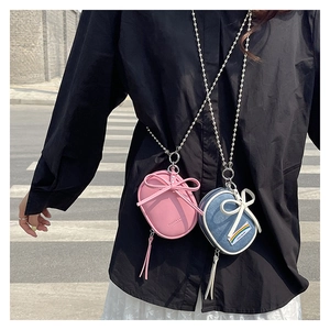 Vista detallada de mini bolsos bandolera con lazo decorativo en cuero rosa y tela denim