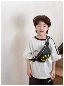 Close-up of kids black leather waist bag featuring yellow smiley face and lettered strap