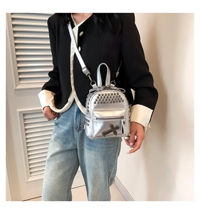 Detail of silver mini backpack with punk studs, mirror PU leather and cross charm