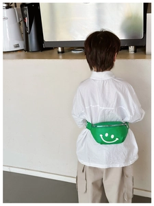 Detailed view of the green kids fanny pack featuring a white smiley face and silver zipper