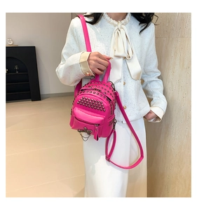 Detail of rose red mini backpack with silver studs and chain on a stylish model