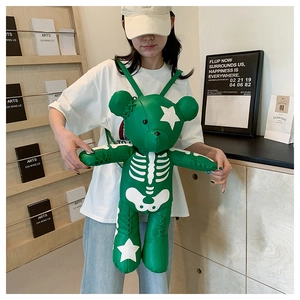 Detailed view of green teddy bear backpack with white skeleton print and star patterns