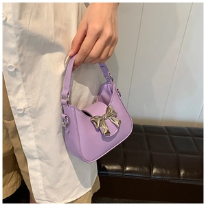 Détail d'un mini sac à main violet avec nœud en métal argenté et rabat à fermoir magnétique