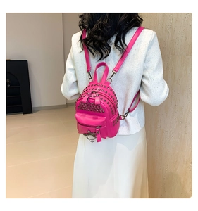 Close-up of pink punk mini backpack with metal studs and chain on a female model