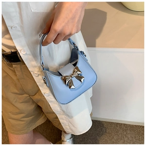 Gros plan du mini sac à main bleu clair avec nœud doré et texture en cuir élégante