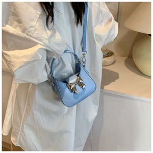 Détail du mini sac bleu clair avec nœud doré et bandoulière réglable pour enfants