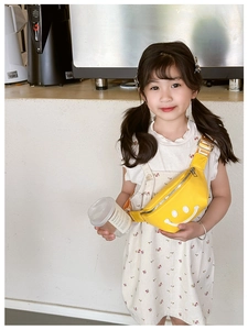 Close-up of bright yellow kids fanny pack with white smiley face and adjustable strap