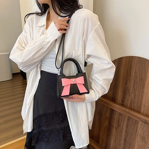 Borsa a tracolla per bambini con fiocco rosa e ciondolo a cuore su camicia bianca