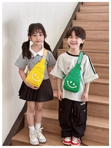 Detail of yellow and green kid's chest bags with smile print and fashion straps