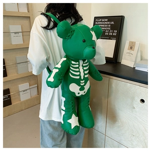 Detail of green bear-shaped leather backpack with bone pattern worn by a person