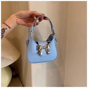 Détail d'un sac à main en cuir verni bleu clair avec un grand nœud en métal argenté