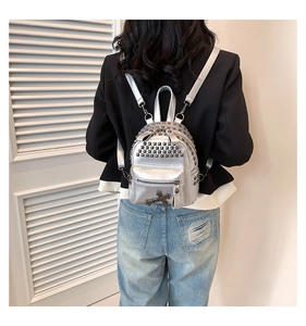 Detail of silver studded mini backpack featuring metallic finish and gothic cross charm