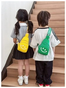 Detail of cute kids chest bags in yellow and green with smile prints and fashion straps