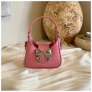 Détail d'un sac à main rose en PU avec nœud en métal argenté sur un tissu en soie blanche