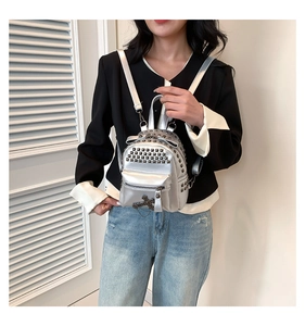 Silver punk mini backpack featuring square rivets and a cross charm on a model's back