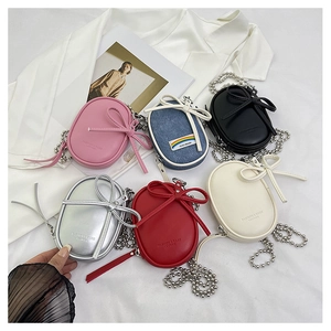 Detalle de mini bolsos bandolera con lazo decorativo y cadena de bolas metálicas