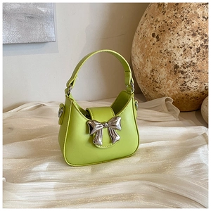Détail du mini sac à main vert avocat avec grande boucle de nœud argenté sur tissu de soie