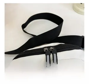 Detail view of smooth double zippers and black nylon strap on kid waist bag