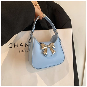 Détail du mini sac à main bleu clair avec nœud en métal argenté et poignée supérieure