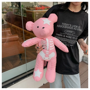 Detailed view of pink faux leather bear plush with bone motifs and star patches