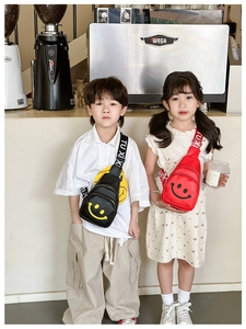 Close-up of kids crossbody bags in black and red with a smiley face and TUXI strap