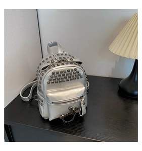 Detail view of silver mini punk backpack featuring metallic studs and cross chain charms