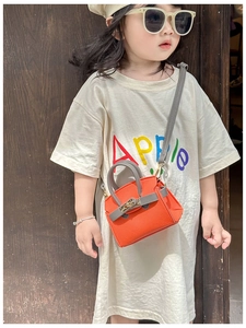 Detail of mini orange textured leather crossbody bag with metallic clasp for kids