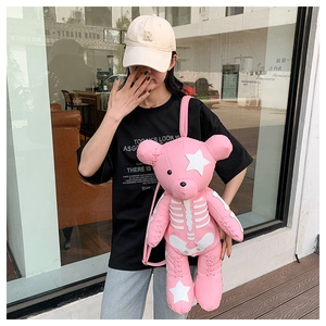 Close-up of pink bear backpack with skeleton print and star patches on street model