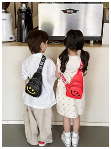 Close-up of kids smiley face crossbody chest bags in black and red glossy fabric