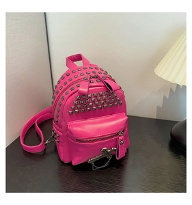 Close-up of pink punk backpack featuring metallic rivets and a cross pendant detail