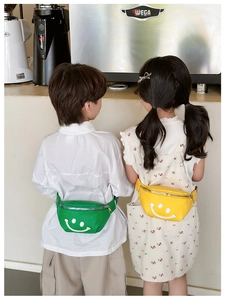 Children wearing yellow and green waist bags with smiley face print in a cafe setting