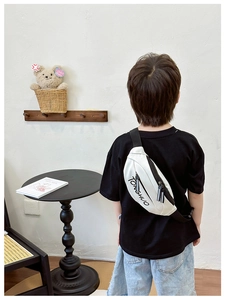 Detail of white canvas waist bag for kids with black TONGSHUO lettering and adjustable strap