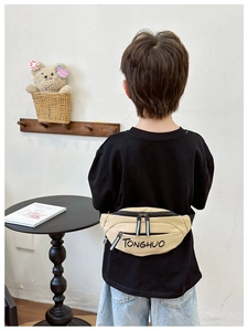 Close-up of khaki kids waist bag with black letter print and reflective zipper pull details