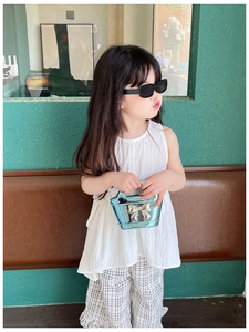 Girl's summer outfit detail with white sleeveless top, plaid pants, and blue bow handbag