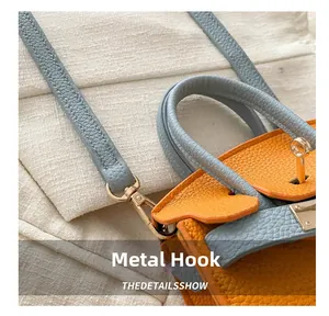 Detail of premium golden hardware hook and textured leather stitching on girl crossbody bag