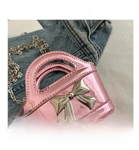 Macro detail of pink metallic handbag with silver bow and delicate chain strap