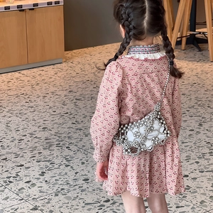 Girl in cherry print dress with a silver hollow-out pearl beaded crossbody shoulder bag