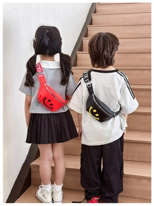 Rear view of children wearing red and black smile face waist bags on wooden stairs