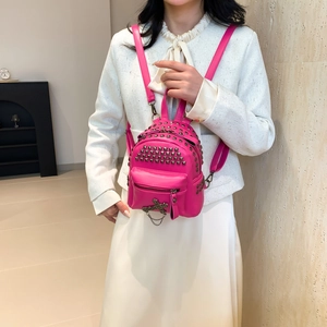 Pink punk style mini backpack with metal studs and chain on a stylish model