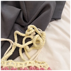 Détail d'un sac à main au crochet rose et beige avec poignées en corde et maille ajourée