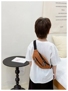 Detail of orange-brown nylon kids waist bag with black XINGHUO letter print and zipper