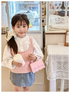 Pink mini leather handbag with scalloped edges worn with a stylish knit vest and skirt