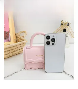 Pink mini crossbody bag with wave edge flap and metal chain shown next to a smartphone