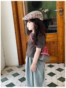 Detail of a mini grey pebbled leather kids crossbody bag with pink handles on a child model